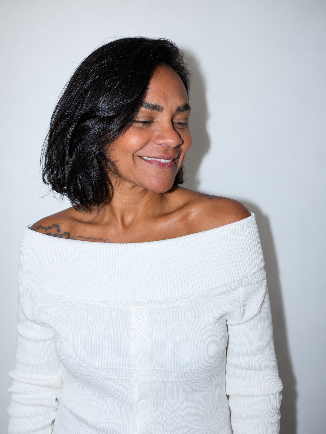 Joyce, criadora do Ponto de Pressão, de blusa branca e sorrindo.